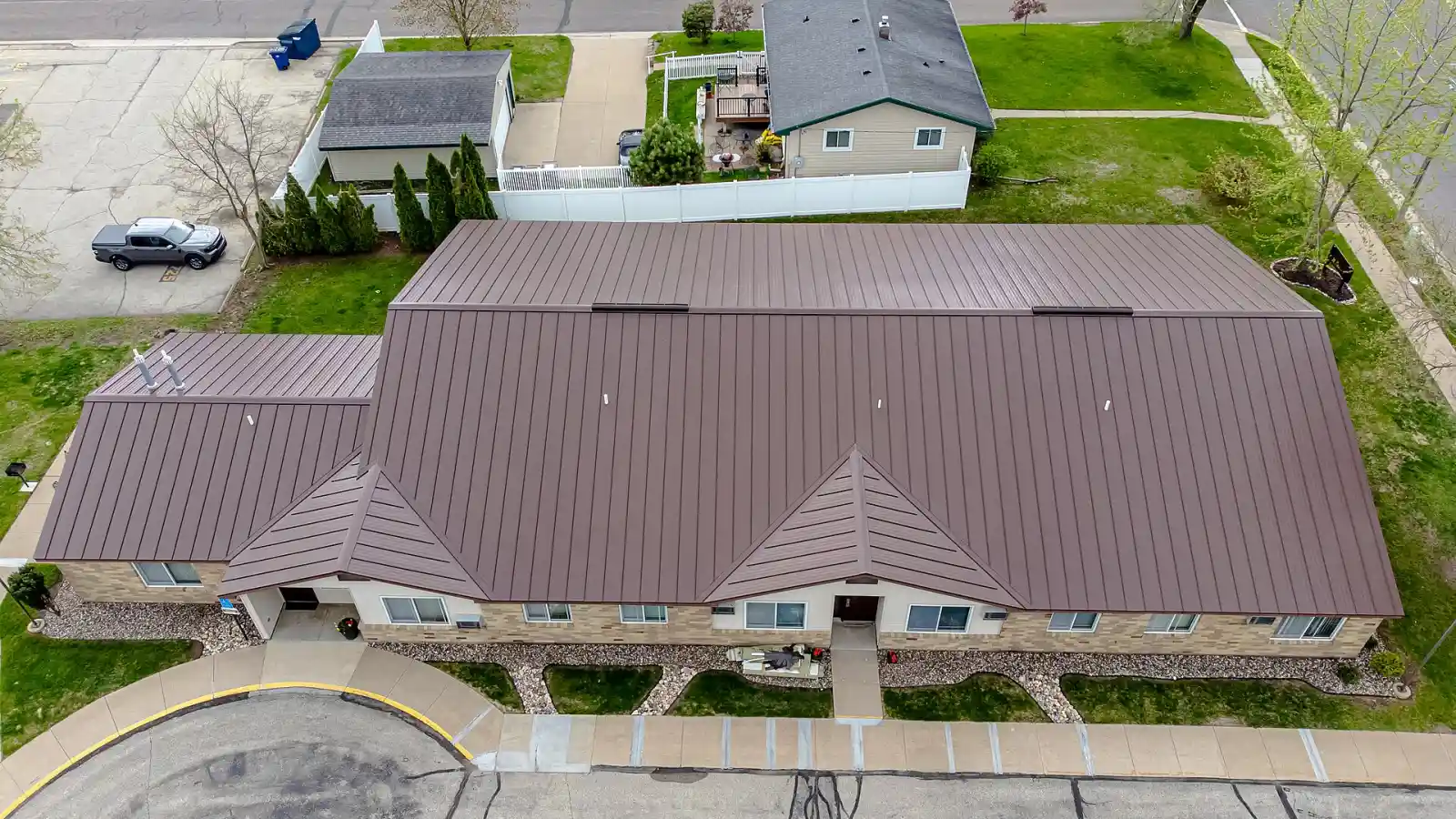 Aerial view of a long single-story building with a new brown standing-seam metal roof
